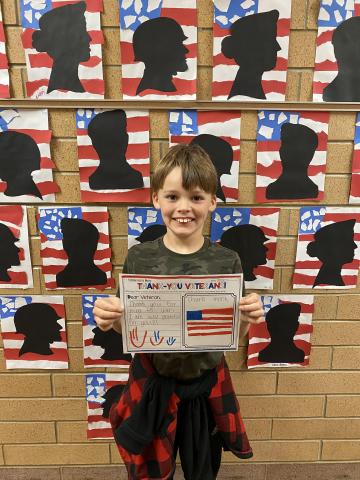 4th grade student holding his thank you card to veterans